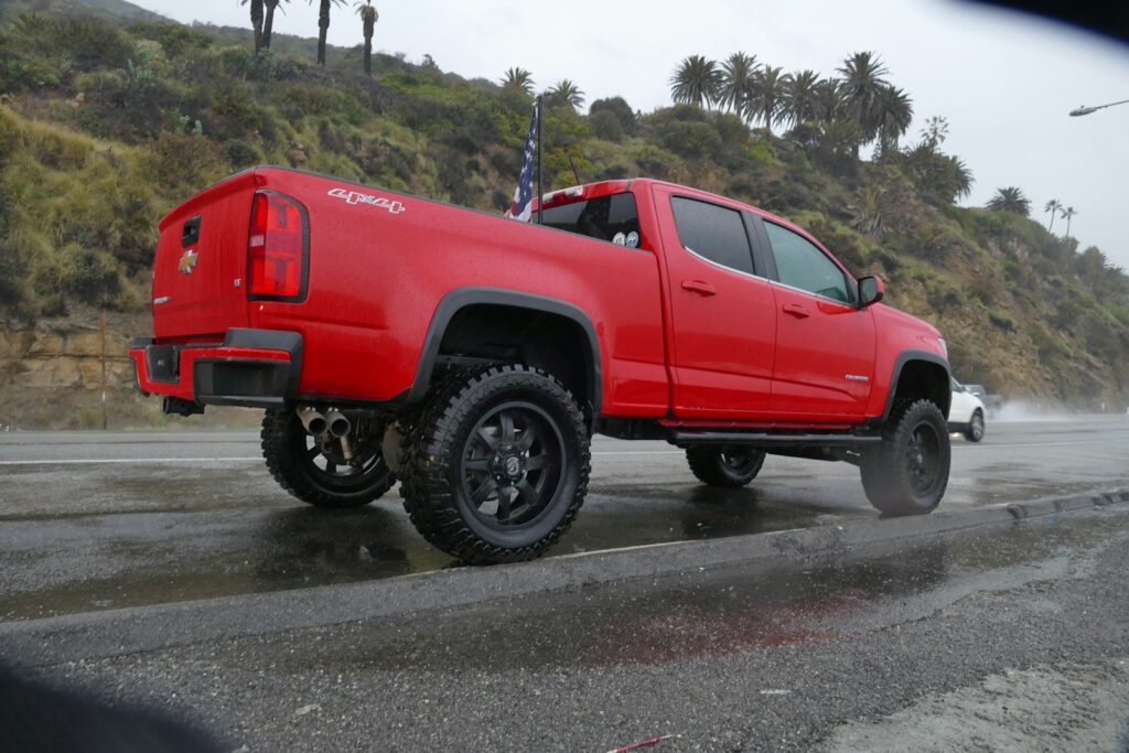 A red truck is driving on a wet road