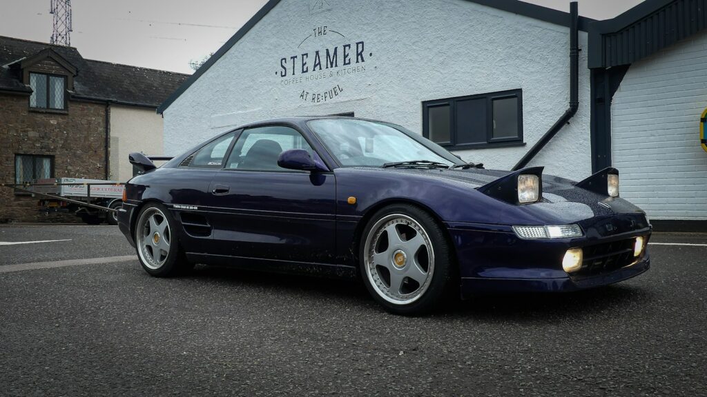 a blue sports car parked in front of a building