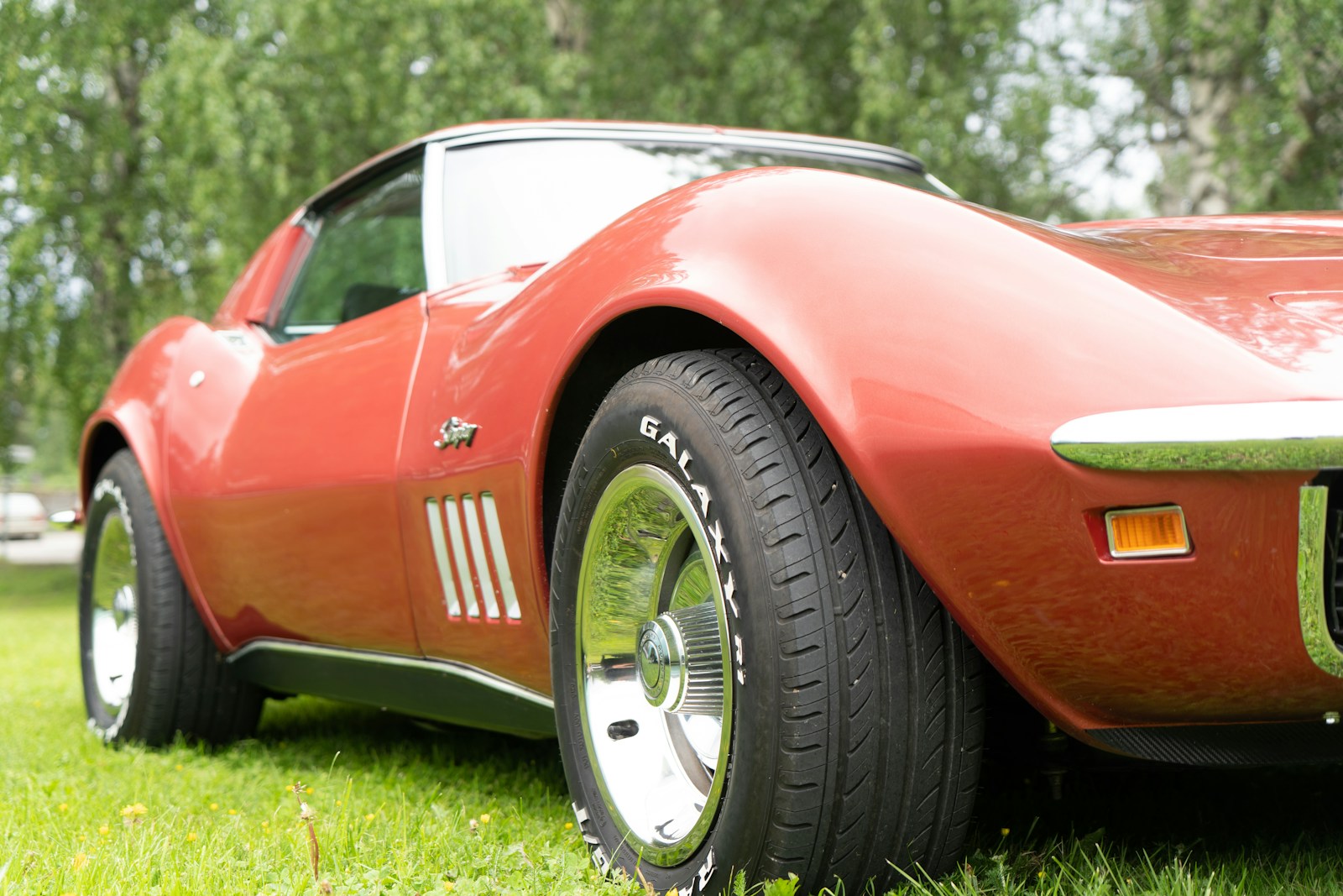 A red vintage sports car parked on a green grassy lawn