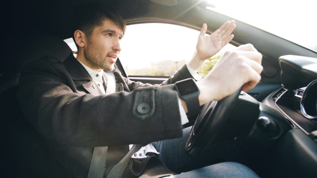 Man driving a car, gesturing with hand