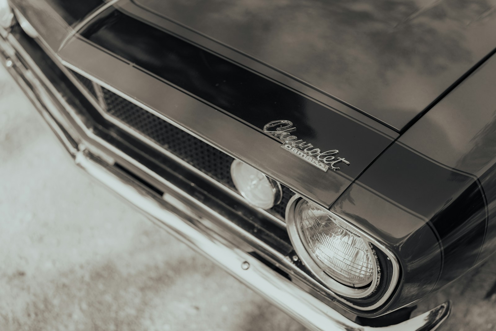 The front hood and headlight of a black Chevrolet Camaro classic car