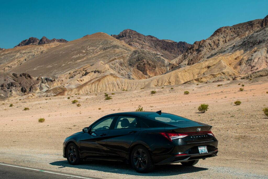 A black car driving down a desert road