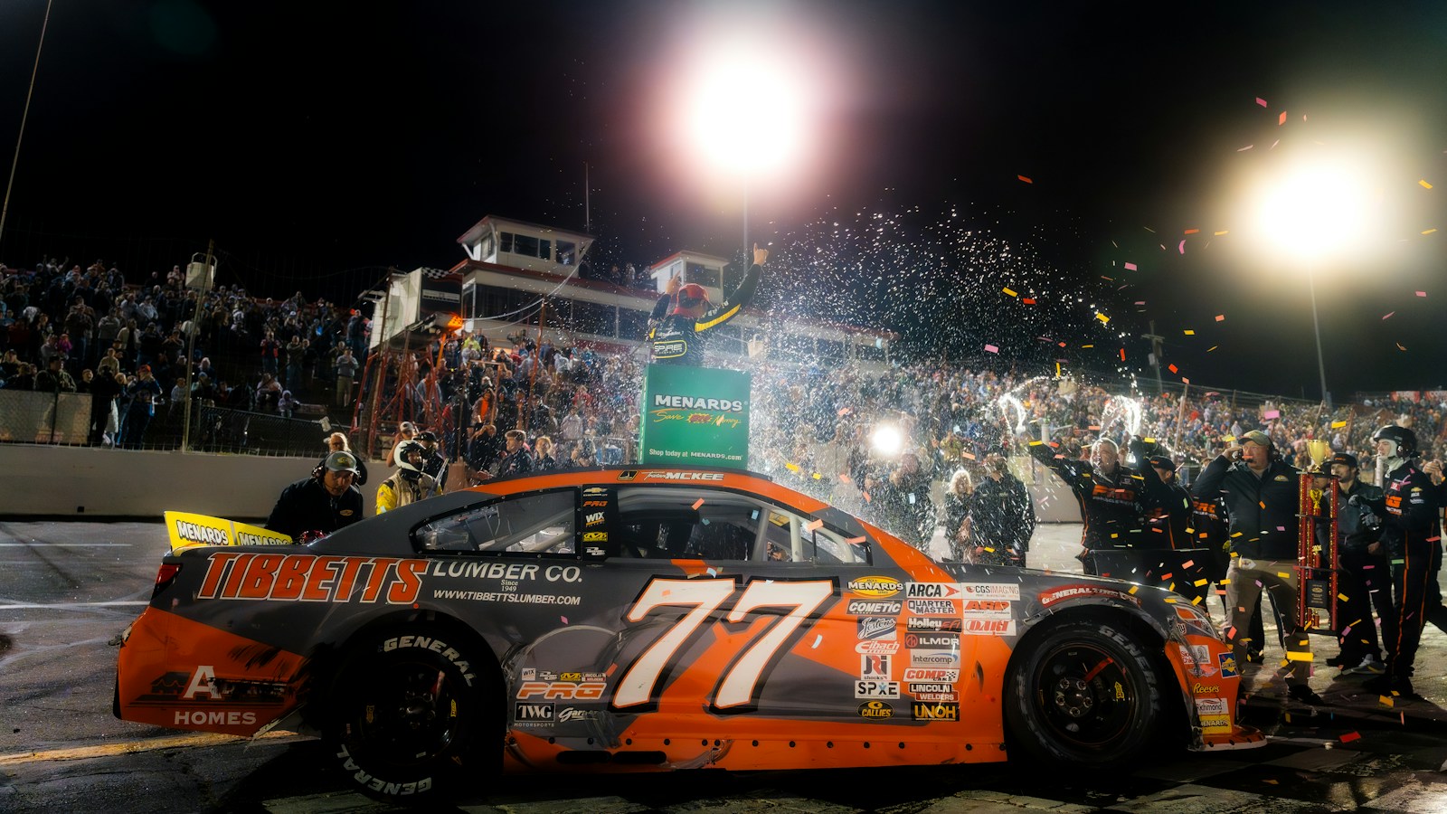 Race car driver celebrates victory with confetti and cheering crowd