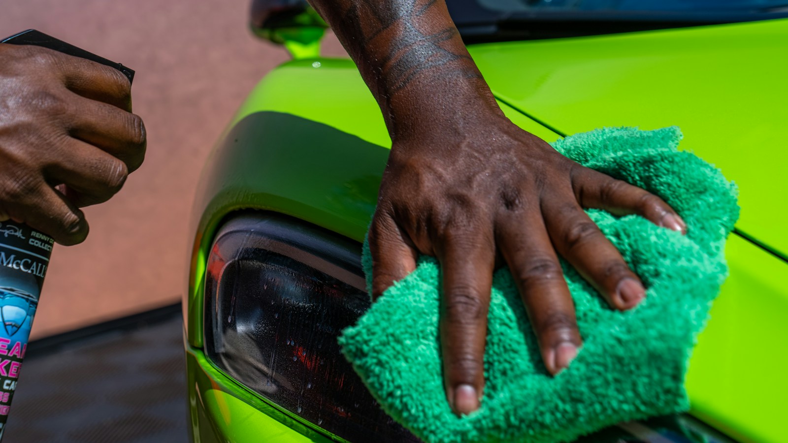 a person cleaning a car with a green cloth