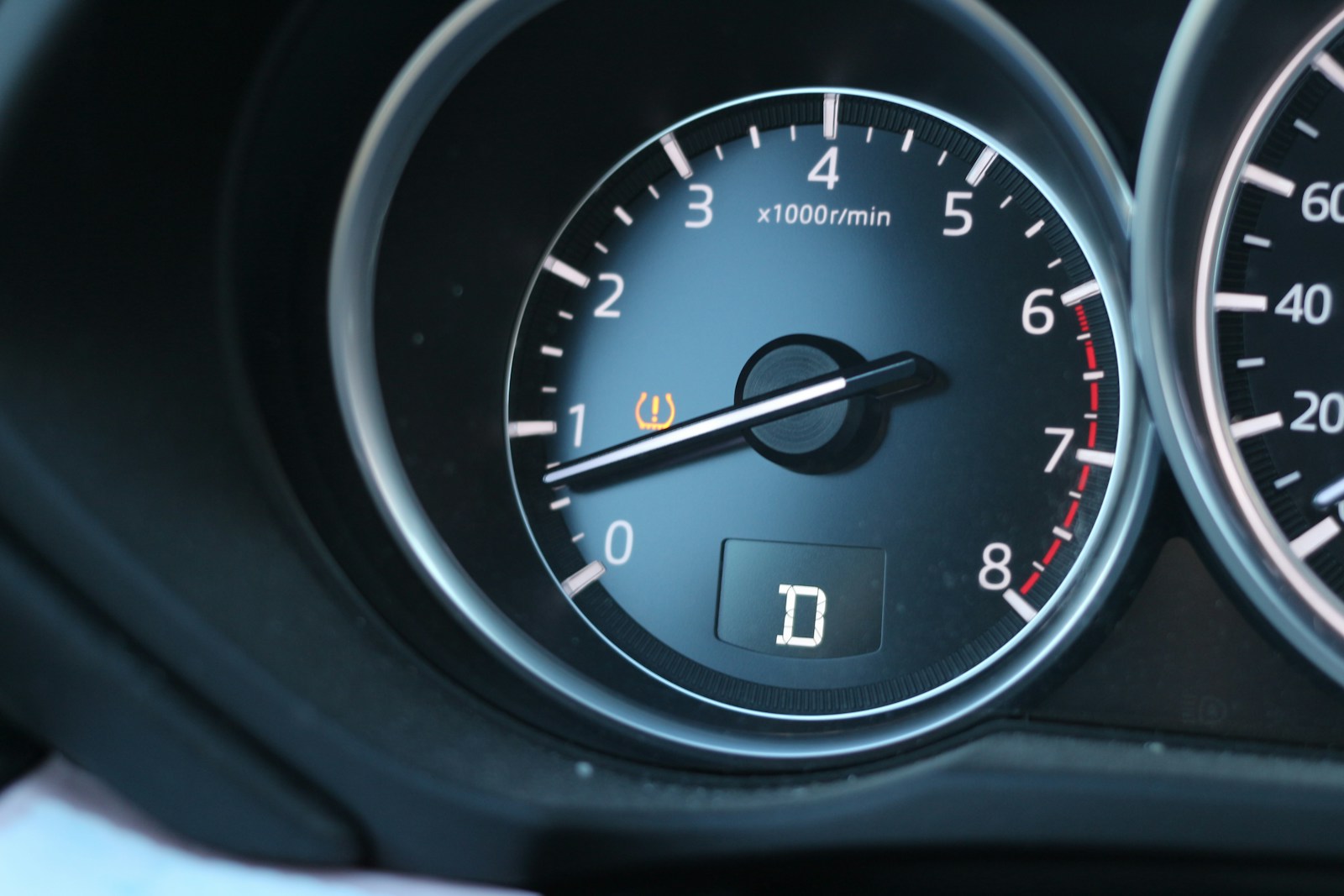Car dashboard with tachometer, drive mode indicator, and warning light