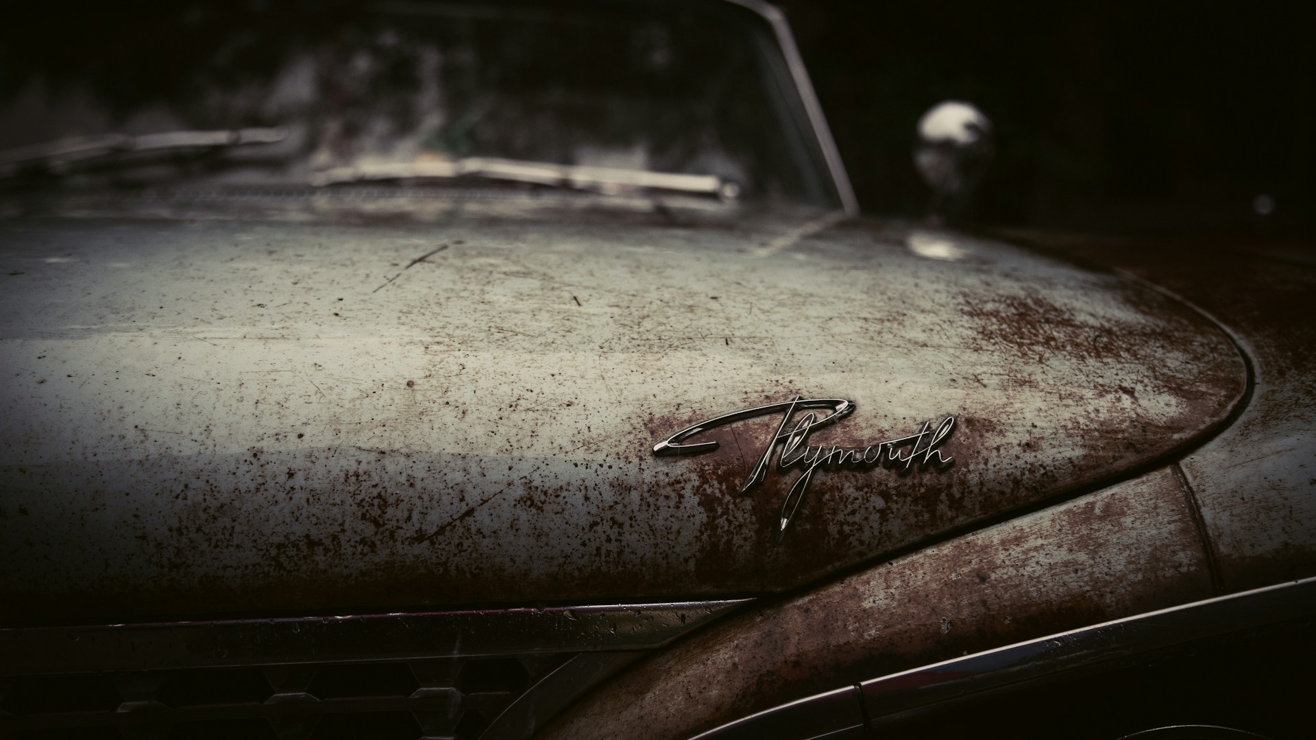 A rusty vintage car sits weathered and worn.