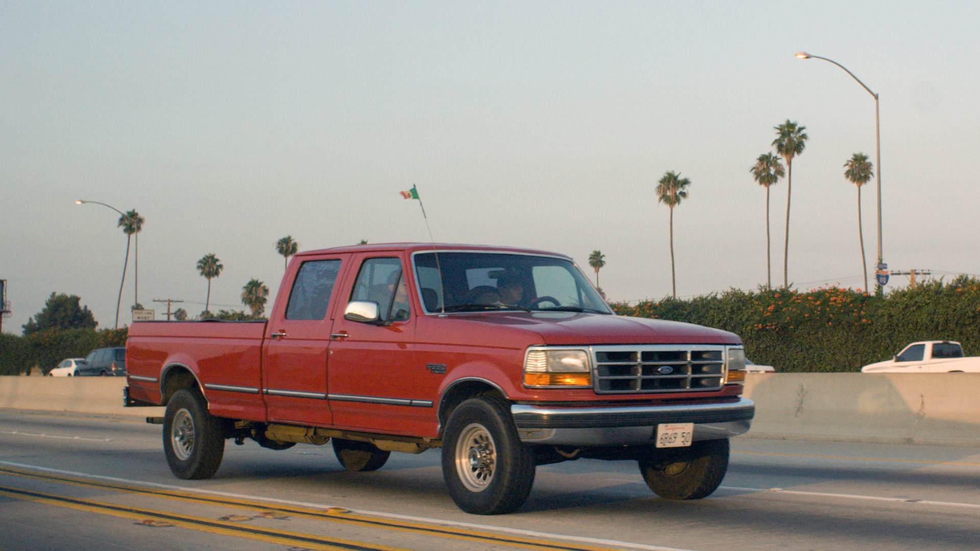 A red pickup truck driving down a highway.